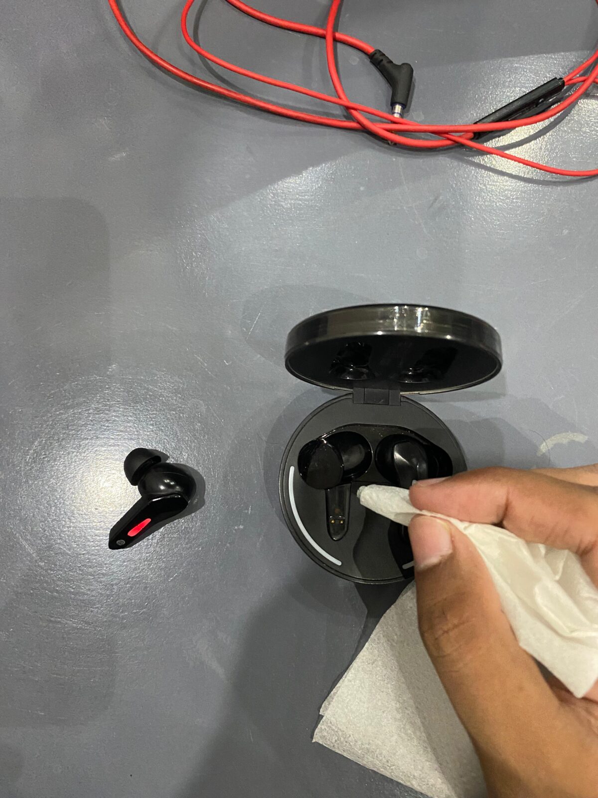 Cleaning the gold charging contacts on the Zero Arcade 900 earbuds with a microfiber cloth.