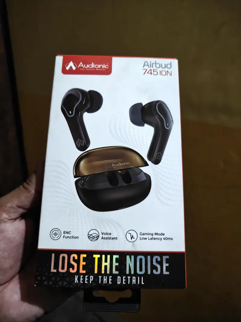 Audionic Airbuds TWS resting on a dark grey mousepad next to a code editor screen, completely restored after the 30-second reset.